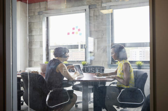Дві жінки працюють з цифровим планшетом у кімнаті для переговорів — стокове фото