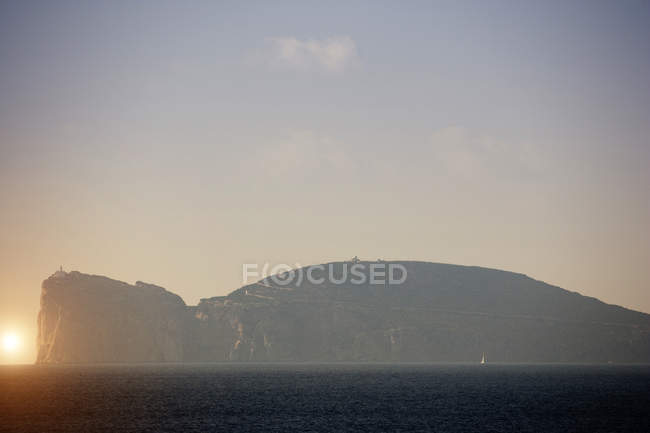 Vista costeira nebulosa com farol no topo do penhasco, Capo Caccia, Sardenha, Itália — Fotografia de Stock
