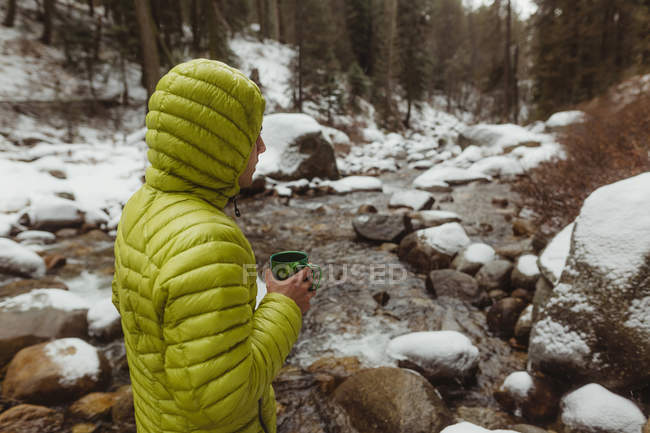 Male hiker with coffee by snowy forest river, Sequoia National Park, California, USA — Stock Photo
