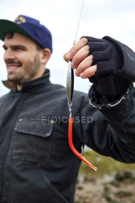 Young man holding fishing line and hook — Stock Photo