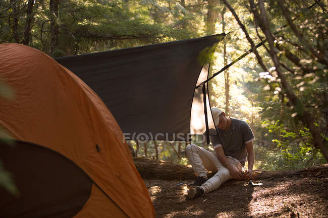 Adolescente ragazzo fissaggio tenda a terra — Foto stock