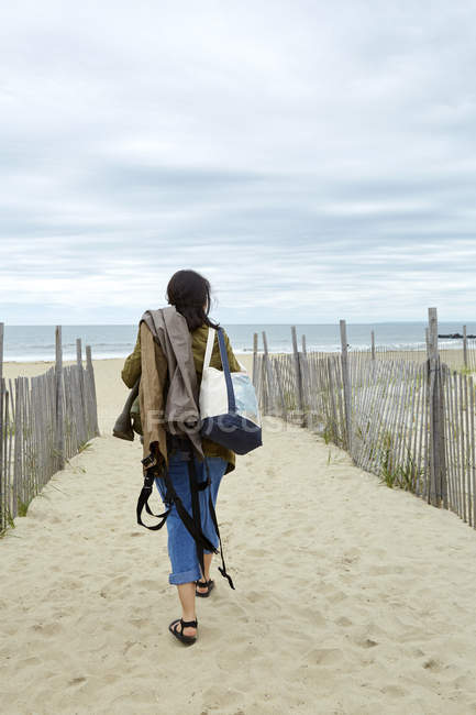Young woman carrying fishing equipment on beach — Stock Photo