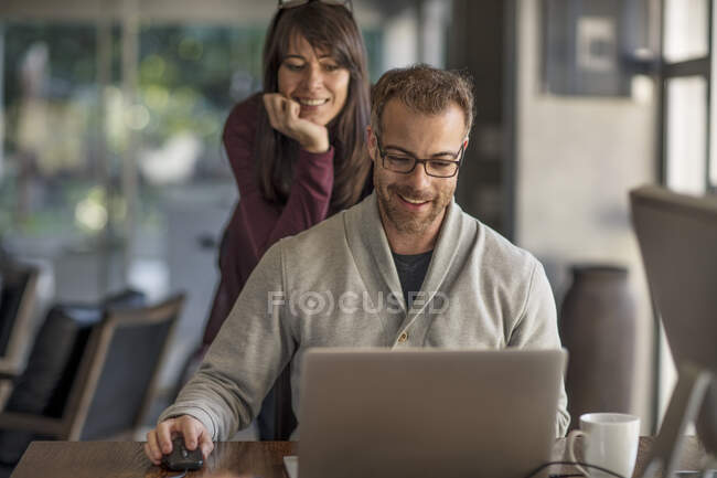 Geschäftsfrau und Mann schauen am heimischen Schreibtisch auf Laptop — Stockfoto