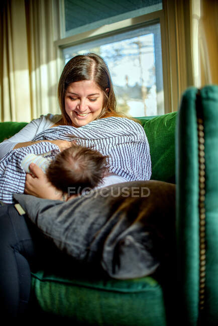 Mother breastfeeding baby on sofa — Stock Photo