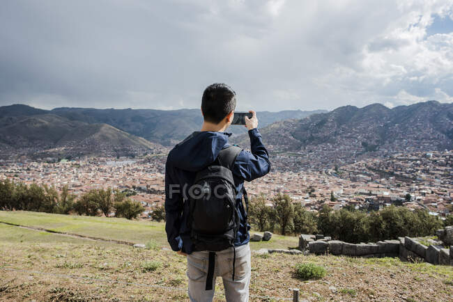 Man photographing view from Sacsayhuaman, using smartphone, Cusco, Peru, South America — Stock Photo