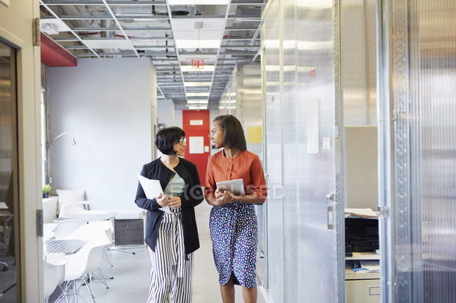 Dos empresarias caminando por el pasillo de oficinas - foto de stock