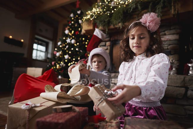 Menina e menino ordenando presentes de Natal — Fotografia de Stock