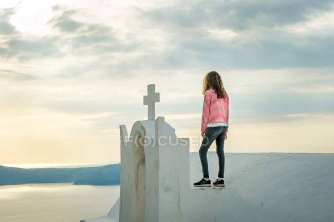 Девушка, стоящая на вершине церкви, Санторини, Кикладес, Греция — стоковое фото