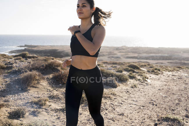 Giovane donna che corre in un arido paesaggio costiero, Las Palmas, Isole Canarie, Spagna — Foto stock