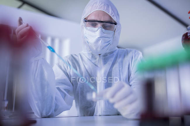 Trabalhador de laboratório usando pipeta longa para transferir líquido para placa de Petri — Fotografia de Stock