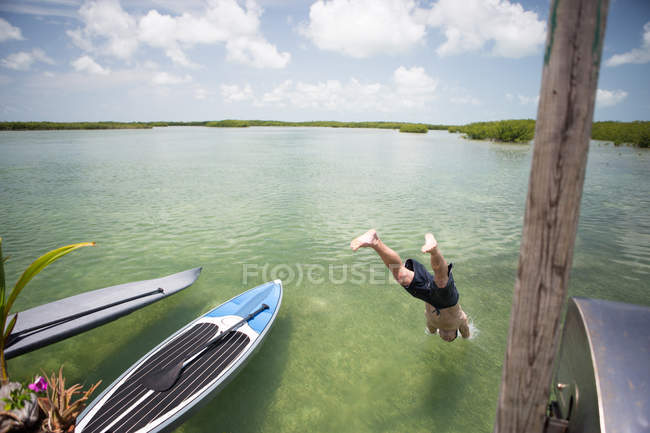 Uomo maturo che si tuffa in acqua dalla costa — Foto stock