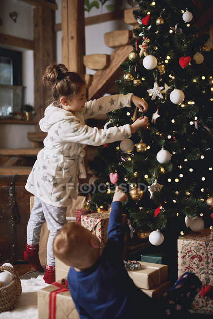 Niña y niño decorando el árbol de Navidad - foto de stock