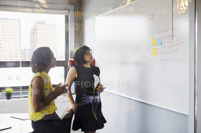 Deux femmes au bureau en utilisant un tableau blanc et des notes collantes — Photo de stock