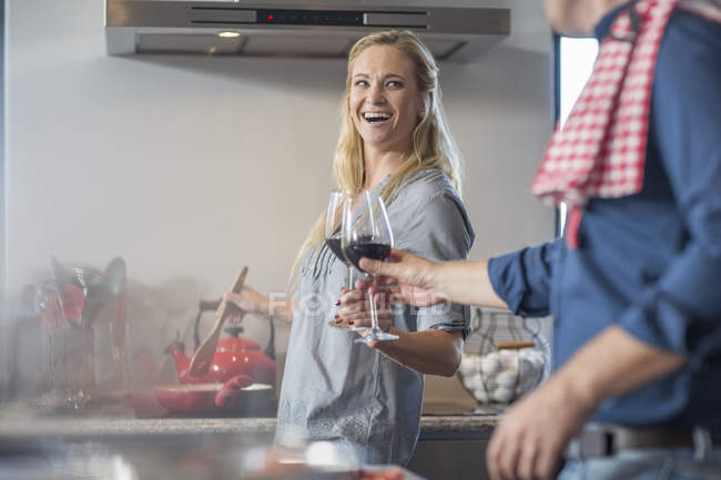 Homme et femme dans la cuisine préparant la nourriture avec un verre de vin — Photo de stock