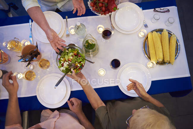 Group of people sitting at table, about to serve food, overhead view — Stock Photo