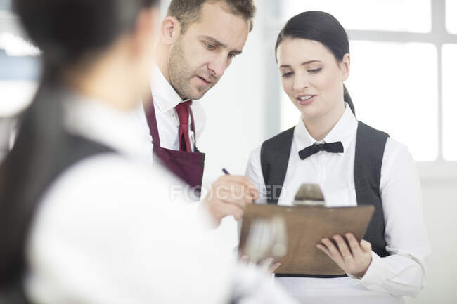 Waiting staff in restaurant, waiter writing on clipboard — Stock Photo