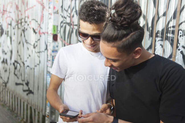 Due giovani mezzi in strada, guardando smartphone — Foto stock