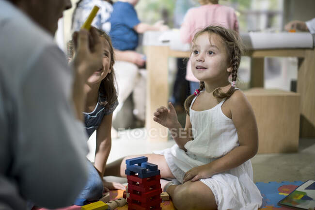 Вчитель і діти граються з будівельними блоками — стокове фото