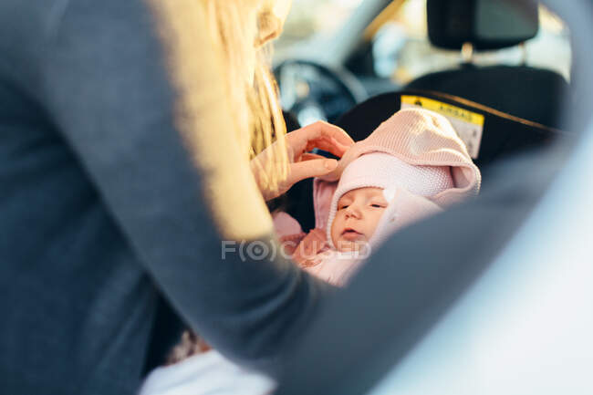 Mother fastening young baby in car seat, mid section view — Stock Photo