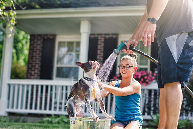 Батько і дочка миють собаку з шлангом — стокове фото