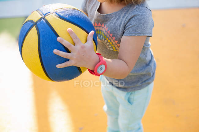 Дівчина тримає баскетбол на ігровому майданчику — стокове фото