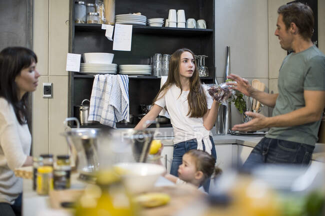 Husband and wife talking to daughter in kitchen, toddler girl reaching for lemons — Stock Photo