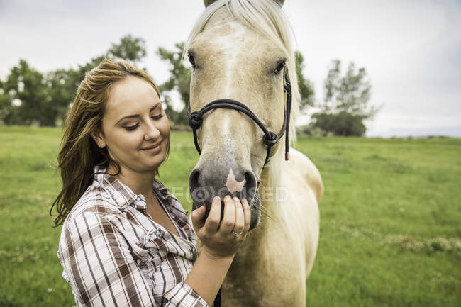Молодая женщина, ласкающая лошадь на ранчо, Бриджер, Монтана, США — стоковое фото