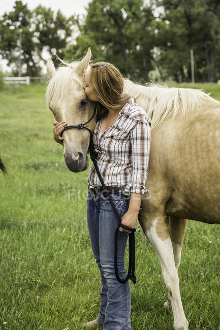 Молодая женщина, целующая лошадь на ранчо, Бриджер, Монтана, США — стоковое фото