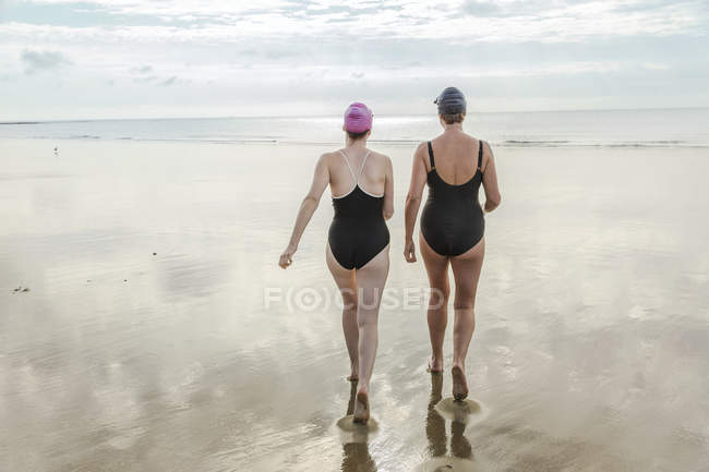 Vista trasera de la madre y la hija caminando al mar - foto de stock