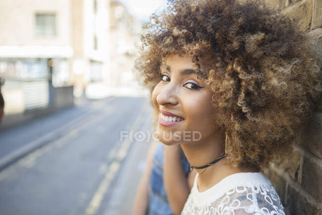 Ritratto di giovane donna appoggiata al muro, sorridente — Foto stock