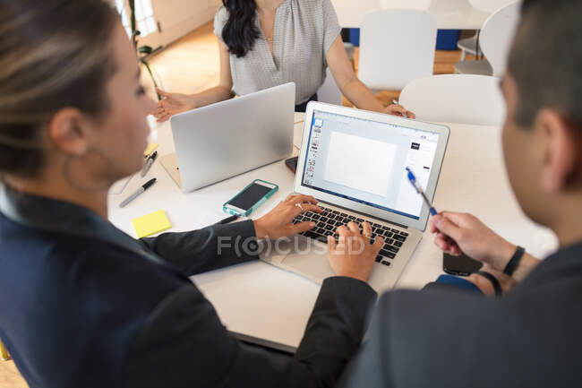 Empresaria escribiendo en la computadora portátil en la reunión de la mesa - foto de stock