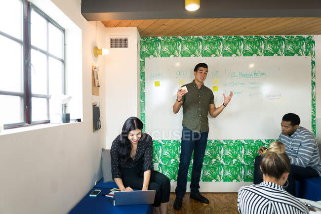 Young adult businessman making presentation in creative meeting room — Stock Photo