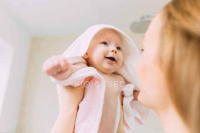 Мать держит малышку дочь завернутую в полотенце — стоковое фото
