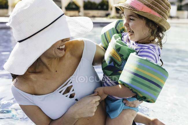 Mother and holding young daughter in outdoor swimming pool — Stock Photo