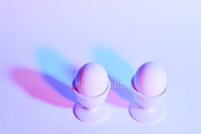 Two eggs in eggcups on purple background — Stock Photo