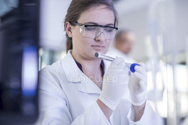 Trabajador de laboratorio escribiendo detalles sobre tubo de ensayo - foto de stock