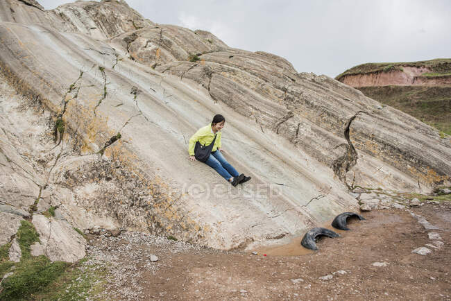Woman sliding down rock slide, Sacsayhuaman, Cusco, Peru, South America — Stock Photo