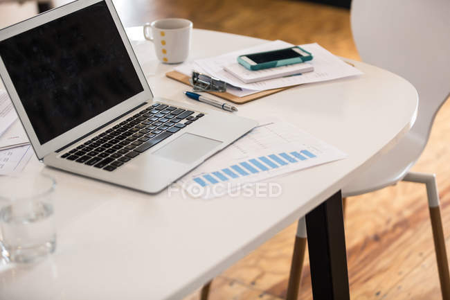 Ноутбук, штрих-чарт и смартфон на рабочем столе — стоковое фото