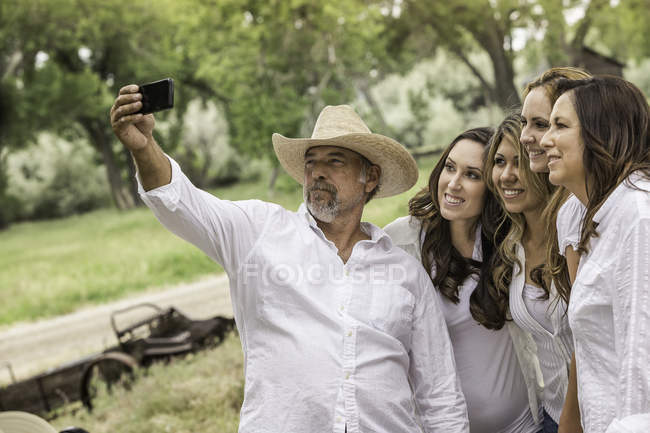 Uomo maturo scattare selfie smartphone con le donne al ranch, Bridger, Montana, Stati Uniti d'America — Foto stock