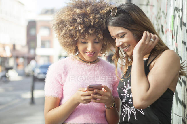 Duas jovens mulheres na rua, olhando para o smartphone — Fotografia de Stock