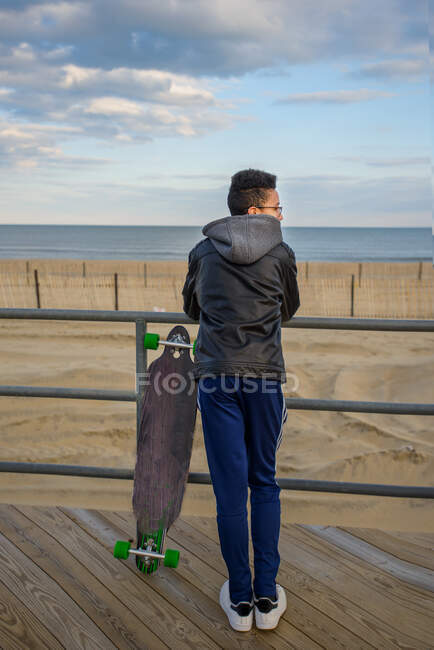 Kleiner Junge lehnt an Geländer, sieht Blick, Skateboard neben ihm, Asbury, New Jersey, USA — Stockfoto