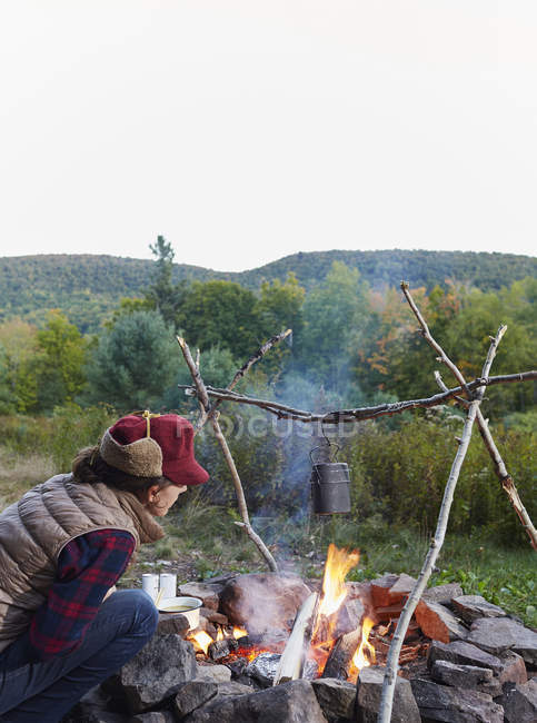 Frau sitzt am Lagerfeuer und kocht Essen, Colgate Lake Wilder Wald, Catskill Park, New York State, USA — Stockfoto