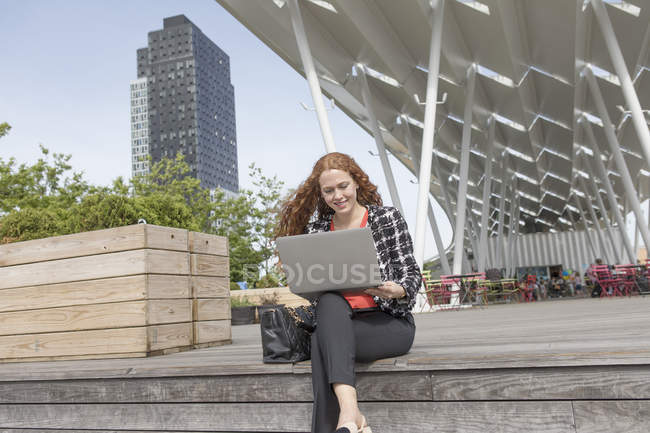 Junge unternehmerin sitzt außerhalb hotel mit laptop, new york, usa — Stockfoto