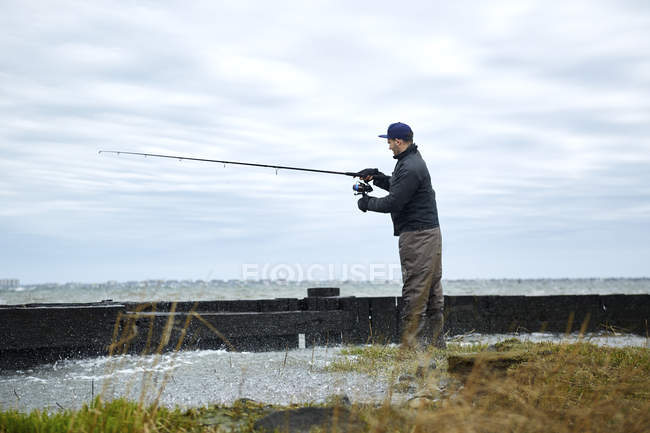 Молодой человек рыбачит на берегу — стоковое фото