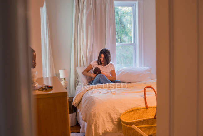 Mother breastfeeding baby on bed — Stock Photo