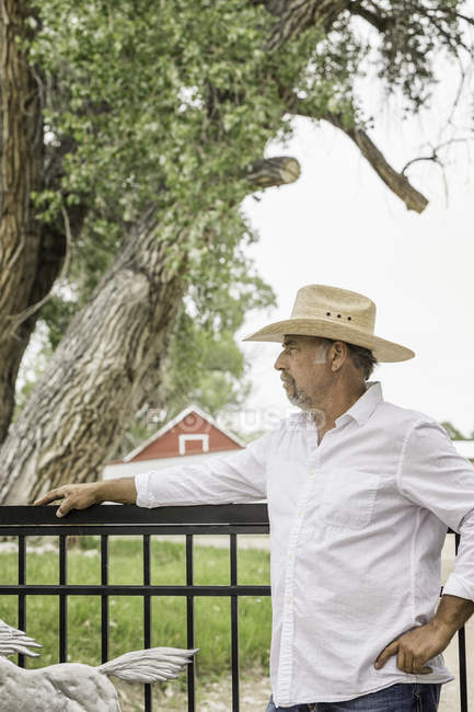 Reifer Mann mit Cowboyhut, angelehnt an Ranch-Tor, Bridger, Montana, USA — Stockfoto