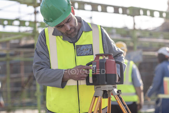 Trabajador de la construcción utilizando equipos de topografía - foto de stock