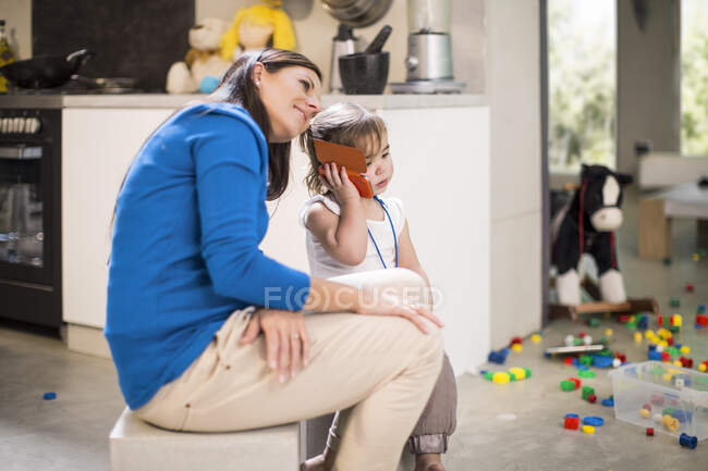 Mother listening in on baby girl's telephone call — Stock Photo