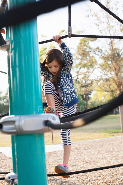 Mädchen steht auf Seilen im Klettergerüst auf Spielplatz — Stockfoto