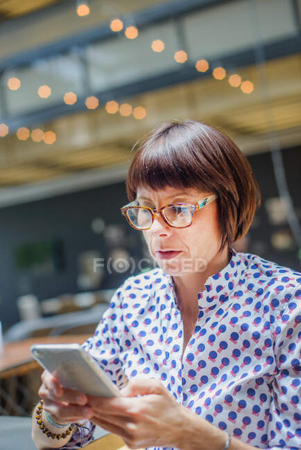Портрет дорослої жінки, що використовує смартфон в офісі — стокове фото